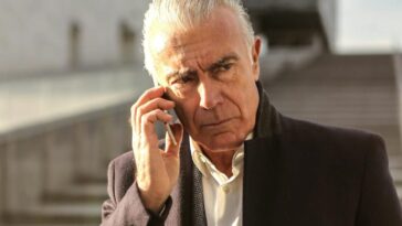 Serious senior businessman using a smartphone outdoors, conveying a professional and pensive mood.