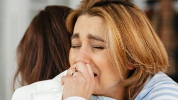 A comforting embrace between two women indoors, highlighting empathy and support.