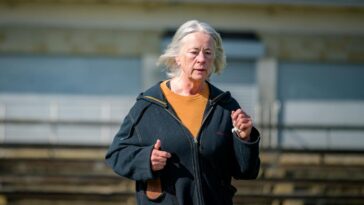 Elderly woman jogging on a bright day, showcasing active lifestyle and wellness in the urban outdoors.