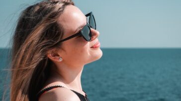 a woman wearing sunglasses looking out over the water