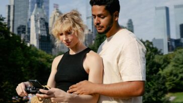 A couple standing together in a city park with skyscrapers in the background, capturing memories.