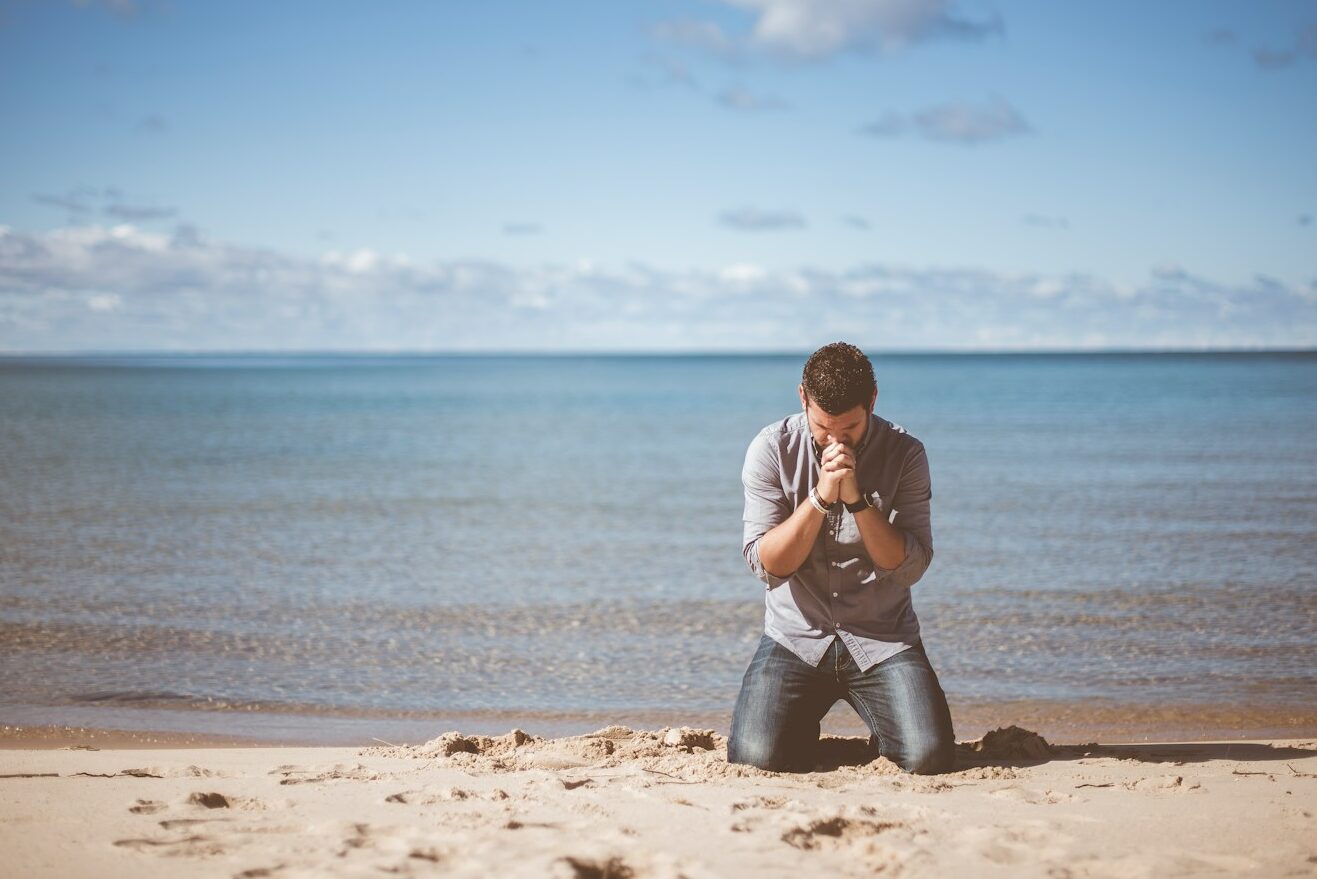 man kneeling down near shore