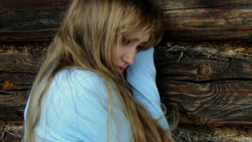 woman leaning on black wooden wall