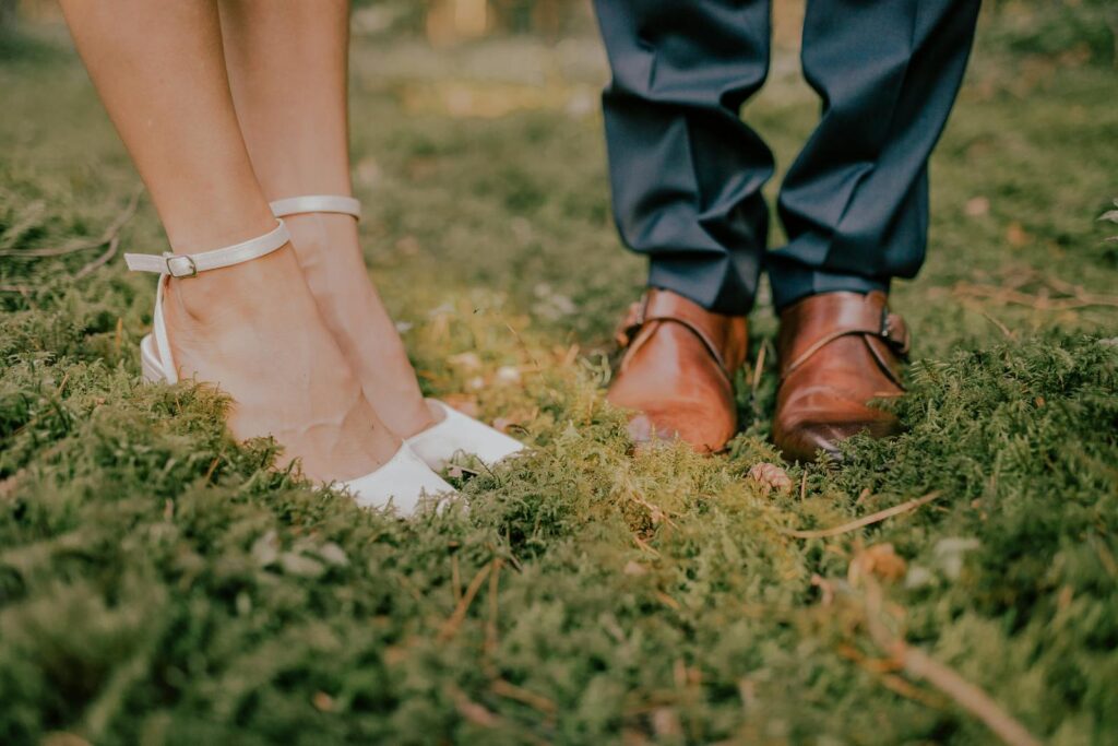 A romantic close-up of bride and groom's shoes on forest ground, symbolizing love and unity.