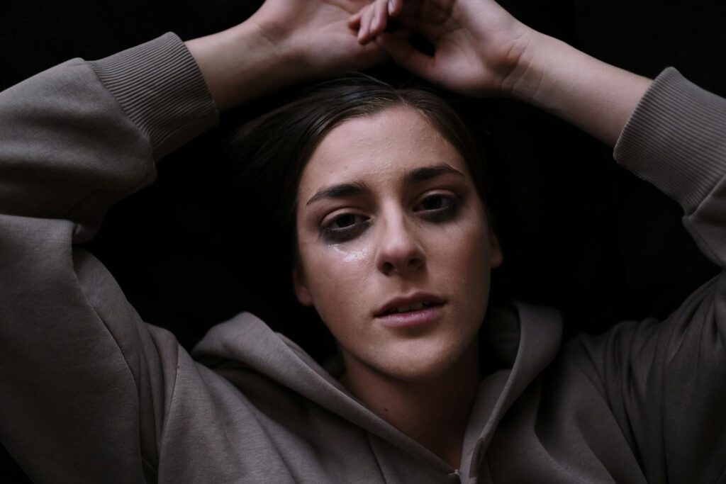 Close-up of a woman expressing sadness with tear-streaked face, conveying deep emotions.
