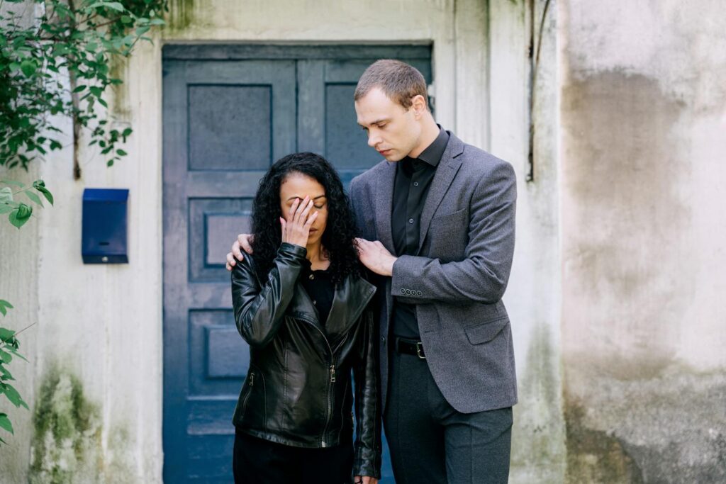 A supportive moment between a couple dealing with emotional distress outdoors.