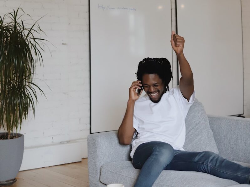 man in white crew neck t-shirt sitting on gray couch