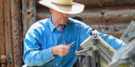 man in blue denim jacket and brown cowboy hat standing beside bicycle during daytime