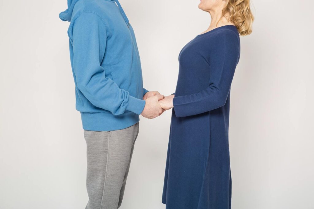 Elderly couple in blue clothing holding hands indoors, symbolizing love and affection.