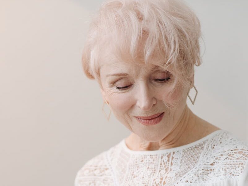 Elegant senior woman with white hair reading a magazine, captures grace and relaxation.