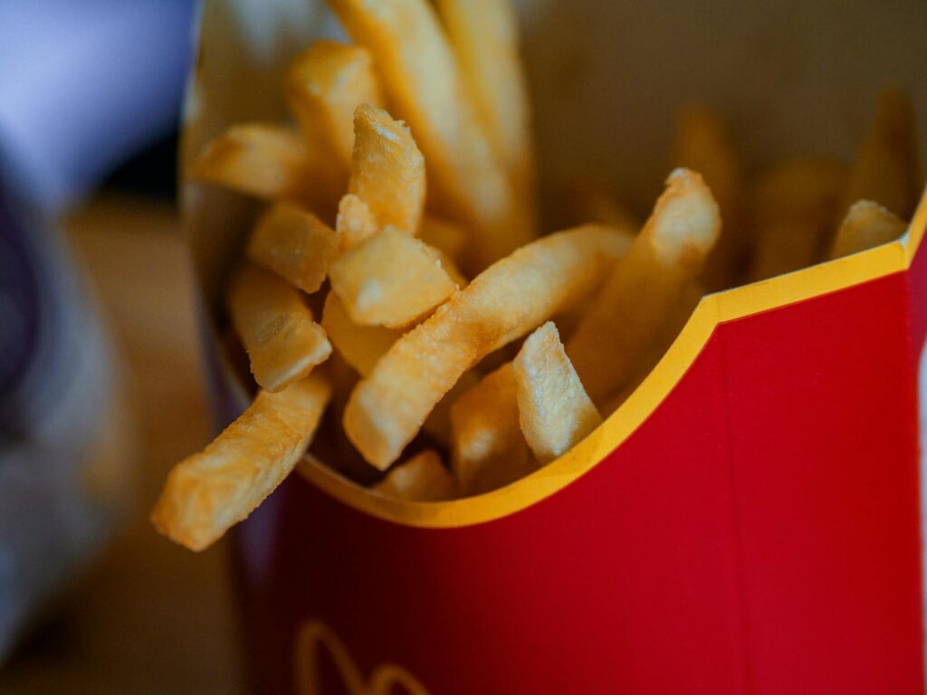 A close-up of crispy and delicious French fries in a takeout container, emphasizing a fast food experience.