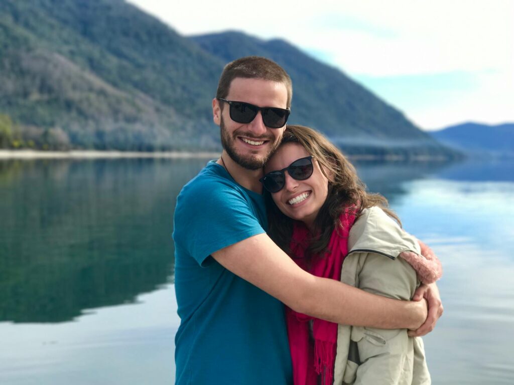 A joyful couple shares a warm embrace by a serene mountain lake, symbolizing love and togetherness.