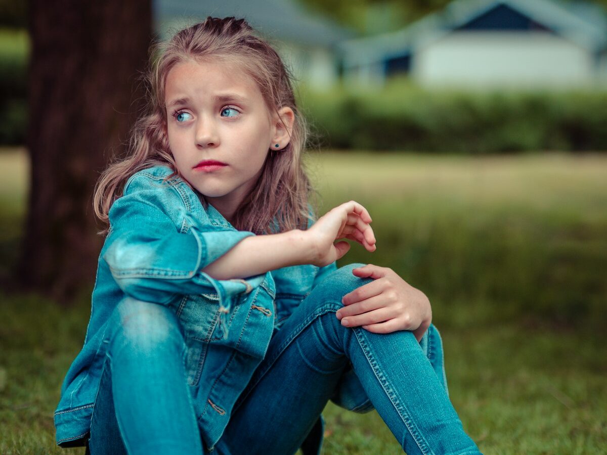 selective focus photography of girl sitting near tree