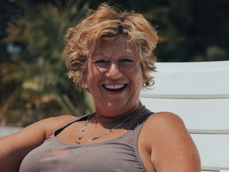 a woman sitting on a white bench smiling