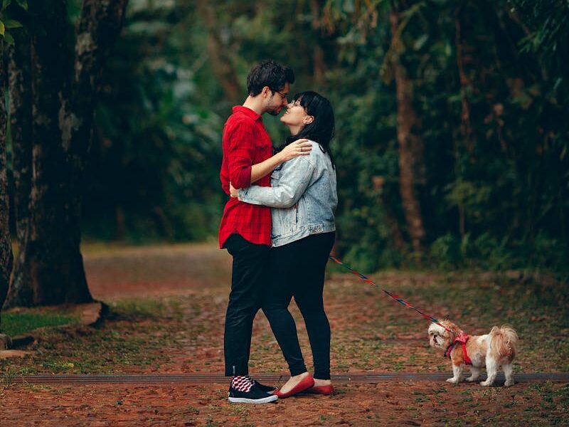 Young couple embracing in a lush forest with their small dog. A moment of affection and togetherness.