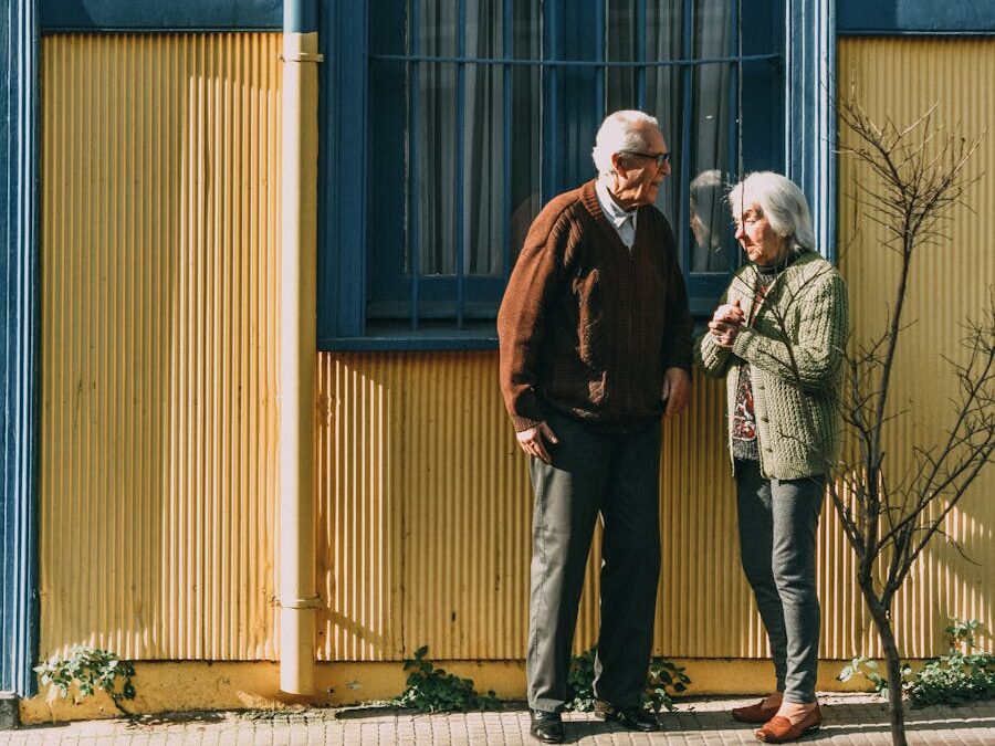 A senior couple standing in front of a colorful building in Valparaíso, enjoying the sunny day.