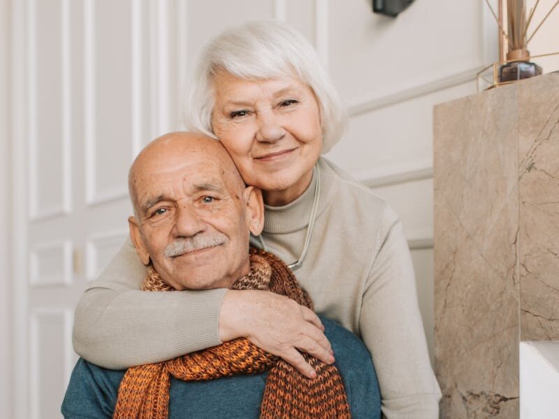 Elderly couple enjoying a warm and loving moment indoors, drinking together.