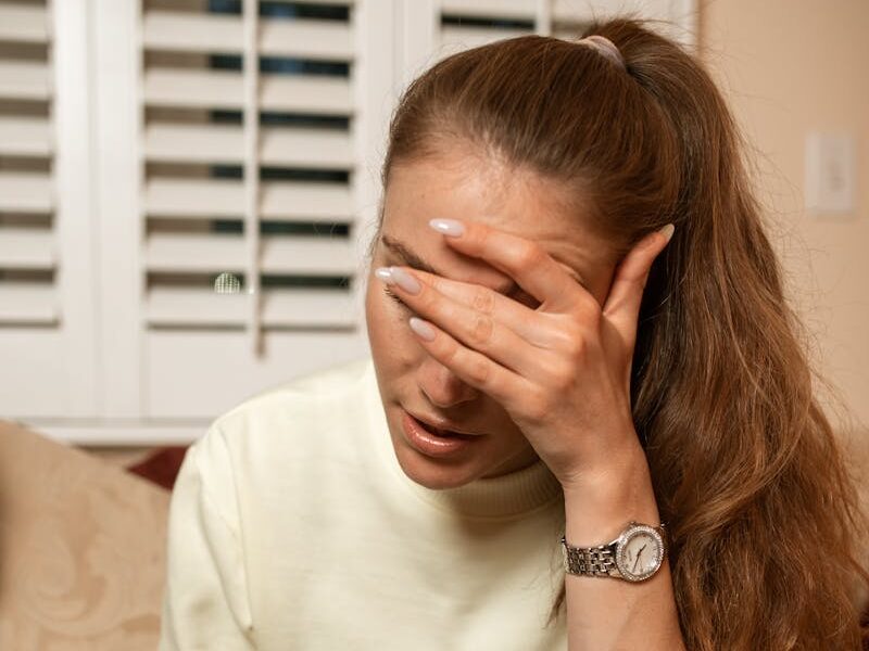 Woman reacts to a pregnancy test result, showing concern indoors.