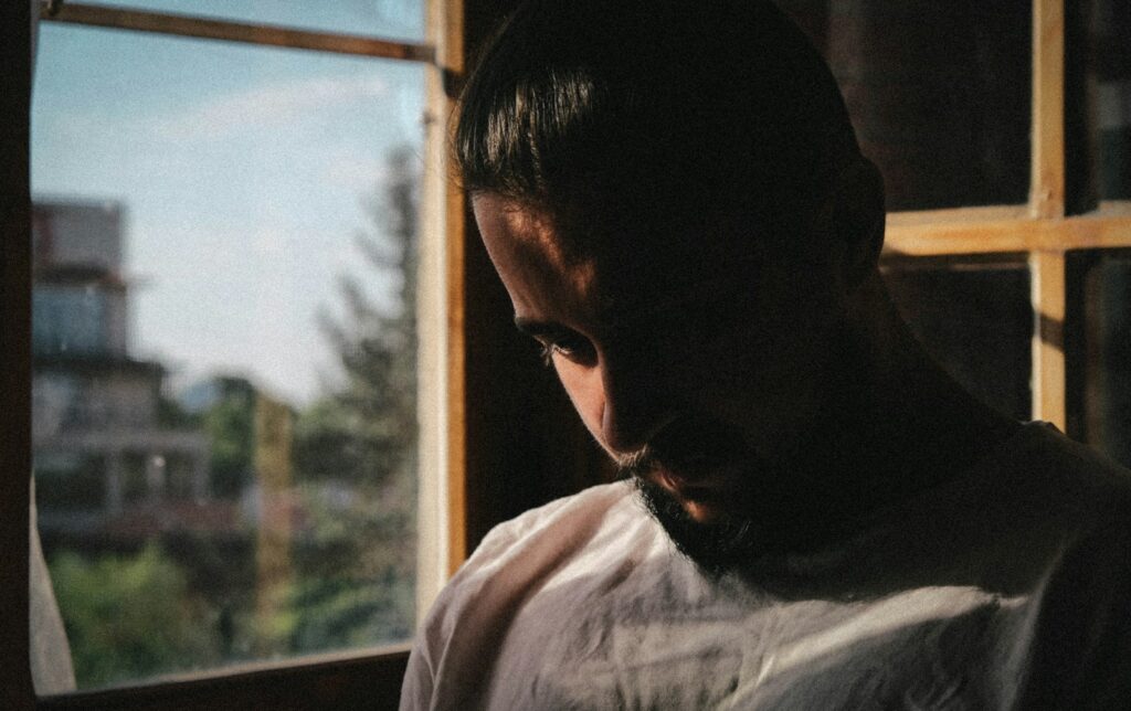 a man looking out of a window in a dark room