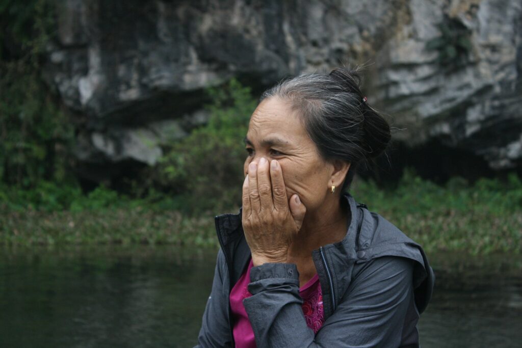 woman in black jacket covering her face with her hand
