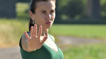 A woman in a green dress making a stop sign