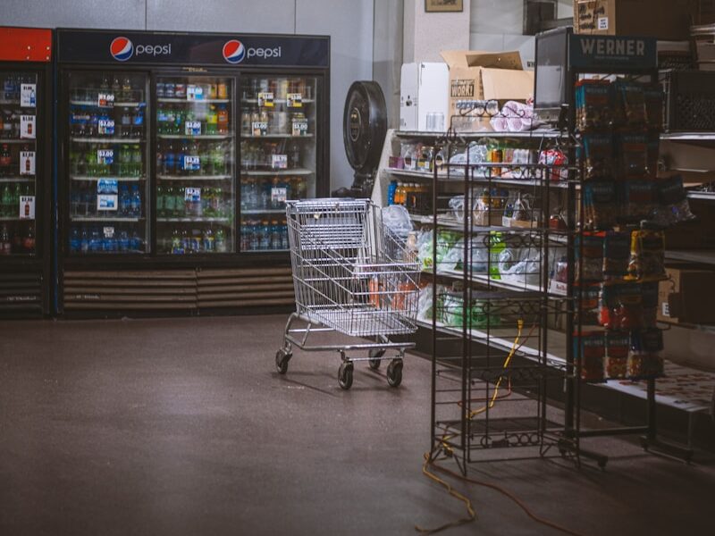 a grocery store with a shopping cart in the middle of the room