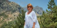 woman in white blouse wearing sunglasses standing on mountain during daytime